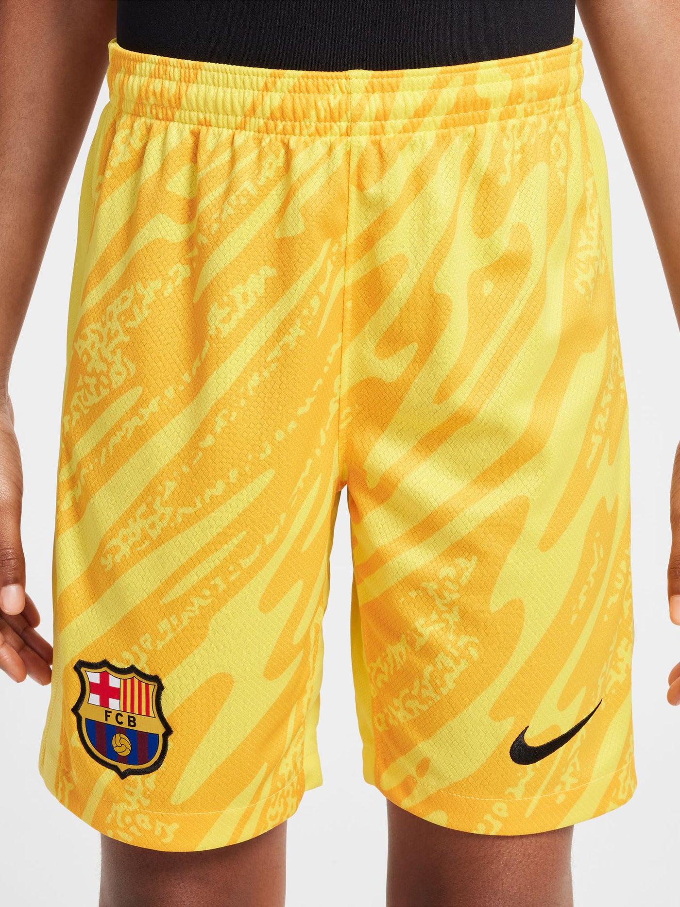 Person wearing bright yellow FC Barcelona goalkeeper shorts with abstract pattern, Nike logo, and club crest.


