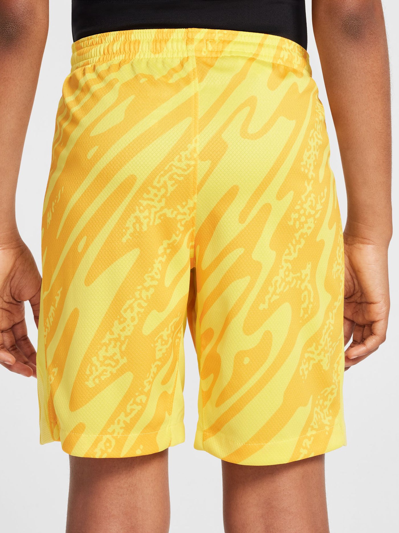 Person wearing bright yellow FC Barcelona goalkeeper shorts with abstract pattern, Nike logo, and club crest.


