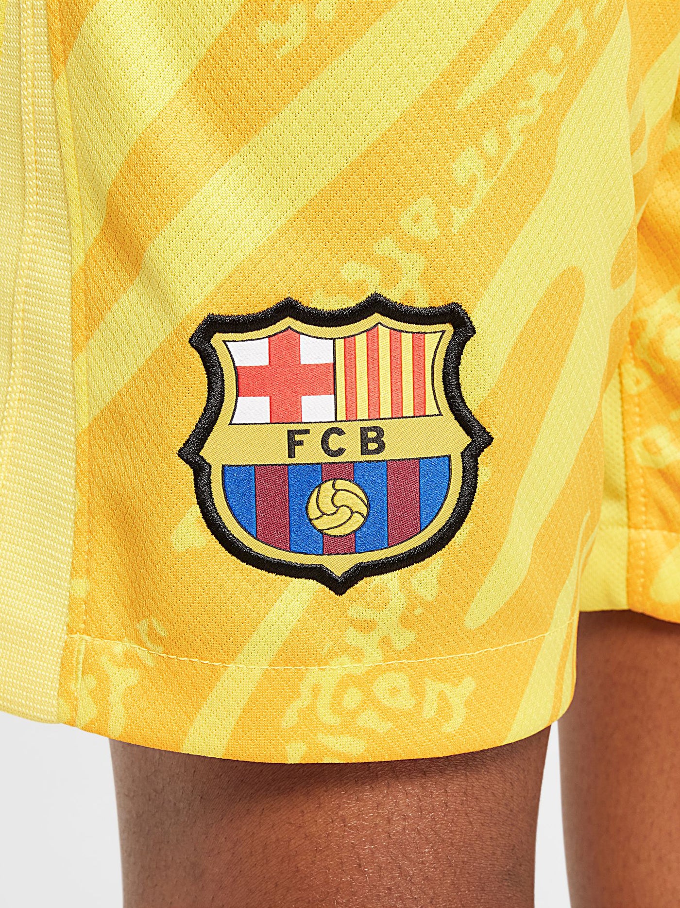 Person wearing bright yellow FC Barcelona goalkeeper shorts with abstract pattern, Nike logo, and club crest.



