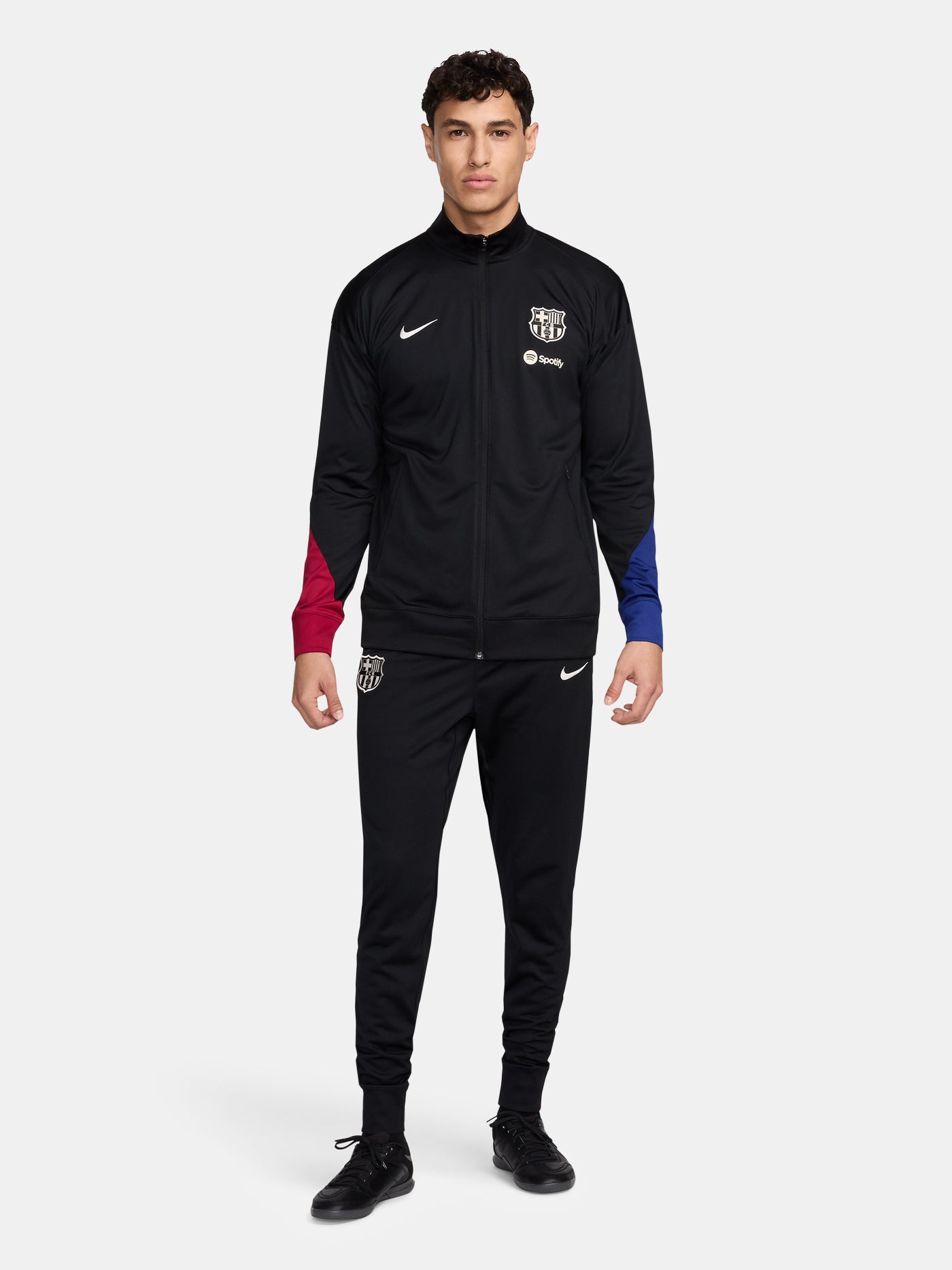 Black FC Barcelona tracksuit with red and blue sleeve cuffs, Nike logo and club crest.