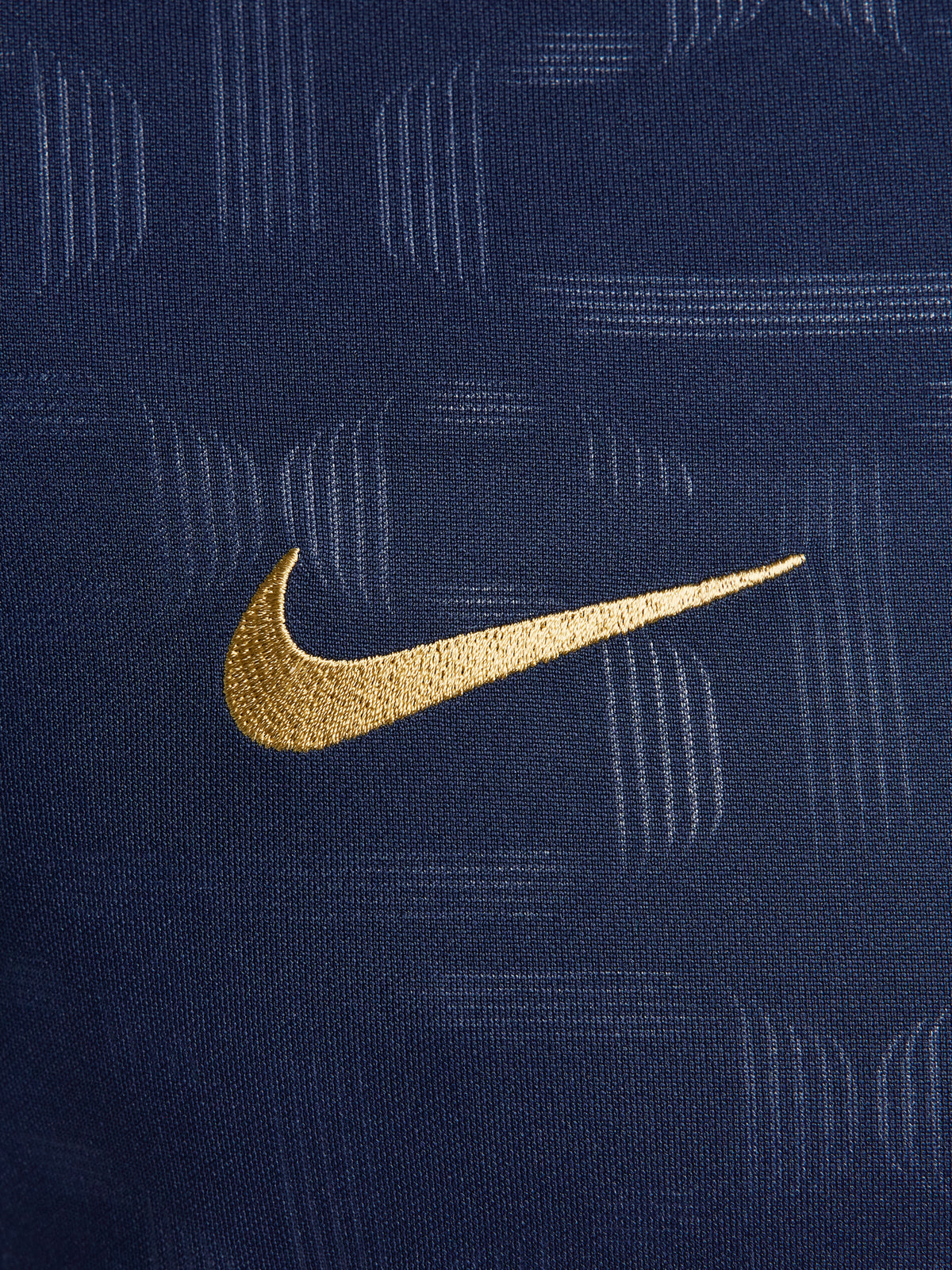 FC Barcelona training shirt in dark navy blue featuring subtle tonal geometric patterns. The shirt displays a golden Nike swoosh on the right chest, the FC Barcelona crest on the left chest, and a bold gold Spotify logo centered across the front.