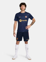 FC Barcelona training shirt in dark navy blue featuring subtle tonal geometric patterns. The shirt displays a golden Nike swoosh on the right chest, the FC Barcelona crest on the left chest, and a bold gold Spotify logo centered across the front.