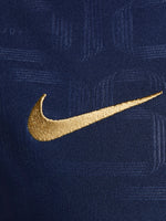 FC Barcelona warm-up shirt featuring a black base with a striking vertical stripe pattern in alternating red and blue. The shirt displays the red Spotify logo in the center, along with the Nike swoosh and FC Barcelona crest, also in red.