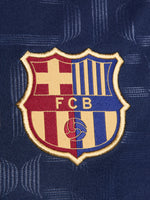 FC Barcelona warm-up shirt featuring a black base with a striking vertical stripe pattern in alternating red and blue. The shirt displays the red Spotify logo in the center, along with the Nike swoosh and FC Barcelona crest, also in red.
