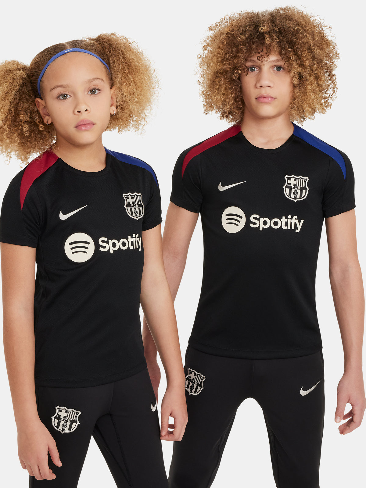 FC Barcelona black kids' training shirt with white Spotify logo and crest, red and blue shoulder details.