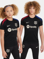 FC Barcelona black kids' training shirt with white Spotify logo and crest, red and blue shoulder details.