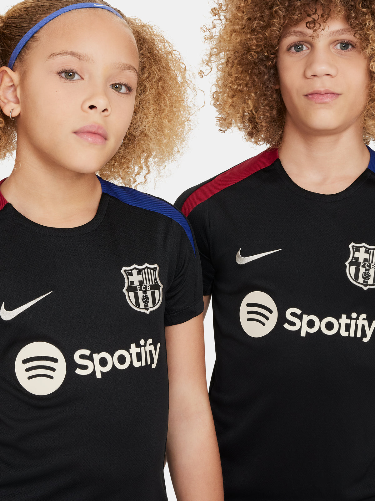 FC Barcelona black kids' training shirt with white Spotify logo and crest, red and blue shoulder details.