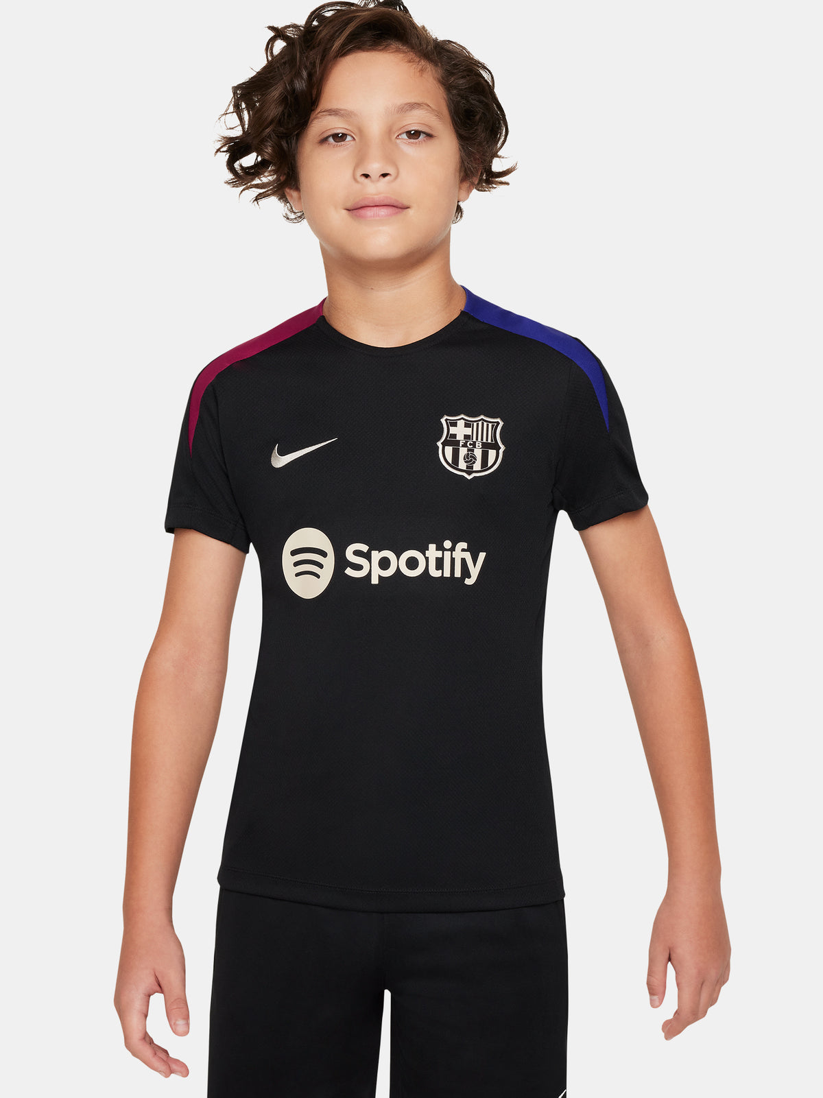 FC Barcelona black kids' training shirt with white Spotify logo and crest, red and blue shoulder details.