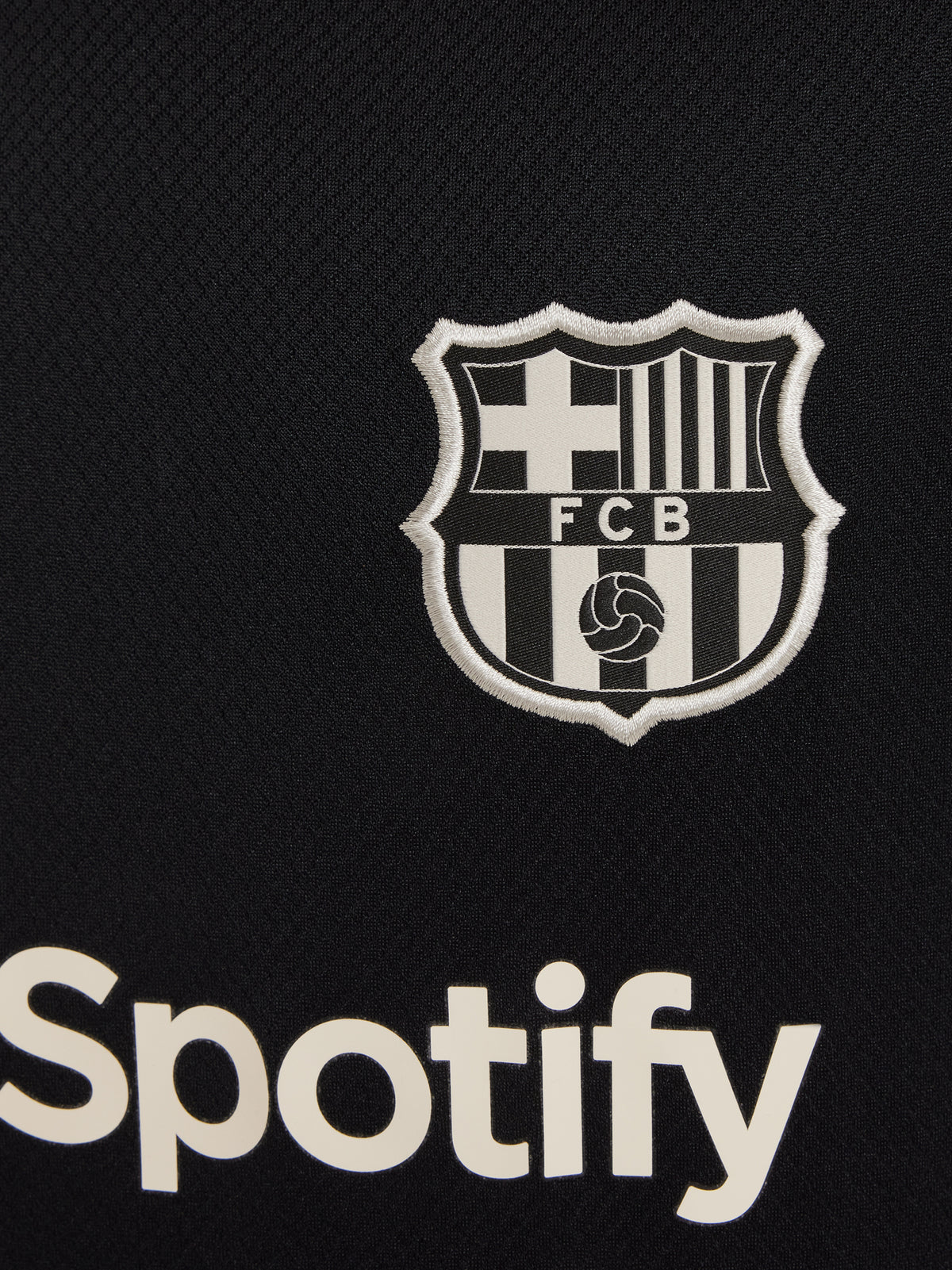 FC Barcelona black kids' training shirt with white Spotify logo and crest, red and blue shoulder details.