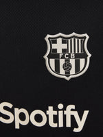 FC Barcelona black kids' training shirt with white Spotify logo and crest, red and blue shoulder details.
