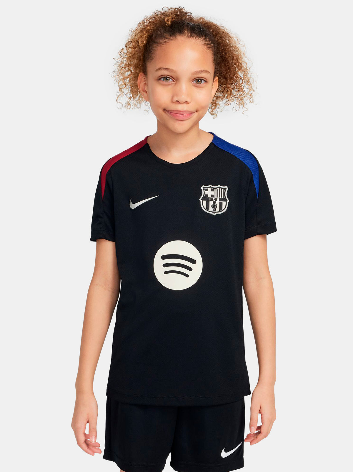 FC Barcelona black kids' training shirt with white Spotify logo and crest, red and blue shoulder details.