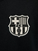 FC Barcelona black kids' training shirt with white Spotify logo and crest, red and blue shoulder details.