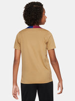 Child wearing an FC Barcelona gold training shirt with short sleeves, red and blue shoulder accents, Nike logo, and Spotify sponsor logo on the chest.