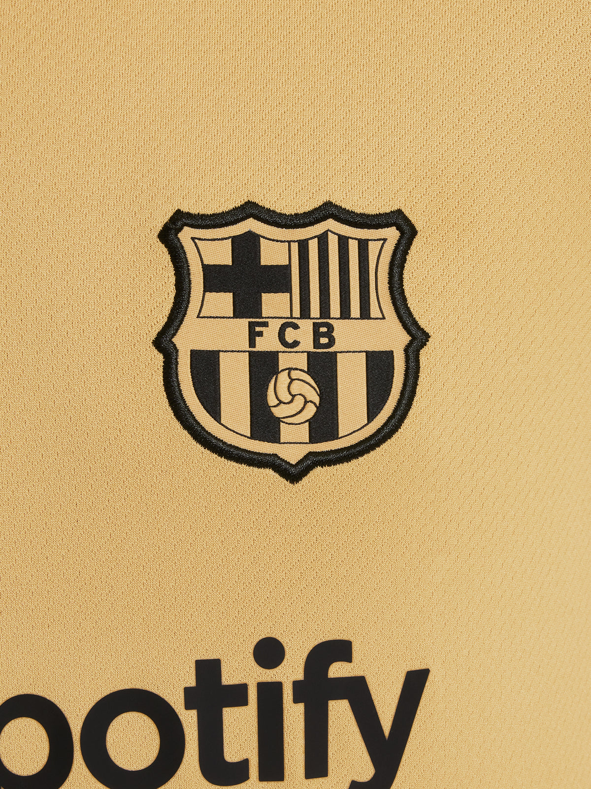 Two children wearing FC Barcelona gold training kits with short sleeves, featuring red and blue shoulder stripes, Nike logos, and Spotify sponsor branding.