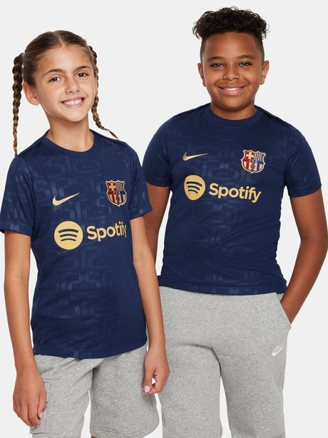 FC Barcelona training shirt in dark navy blue featuring subtle tonal geometric patterns. The shirt displays a golden Nike swoosh on the right chest, the FC Barcelona crest on the left chest, and a bold gold Spotify logo centered across the front.