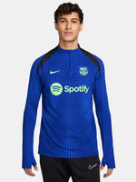 FC Barcelona long-sleeve training top in bright royal blue with vertical textured lines. Features neon green Spotify sponsor logo in the center, Nike logo on the right chest, and FC Barcelona crest on the left chest. Shoulders and upper sleeves have black accents.