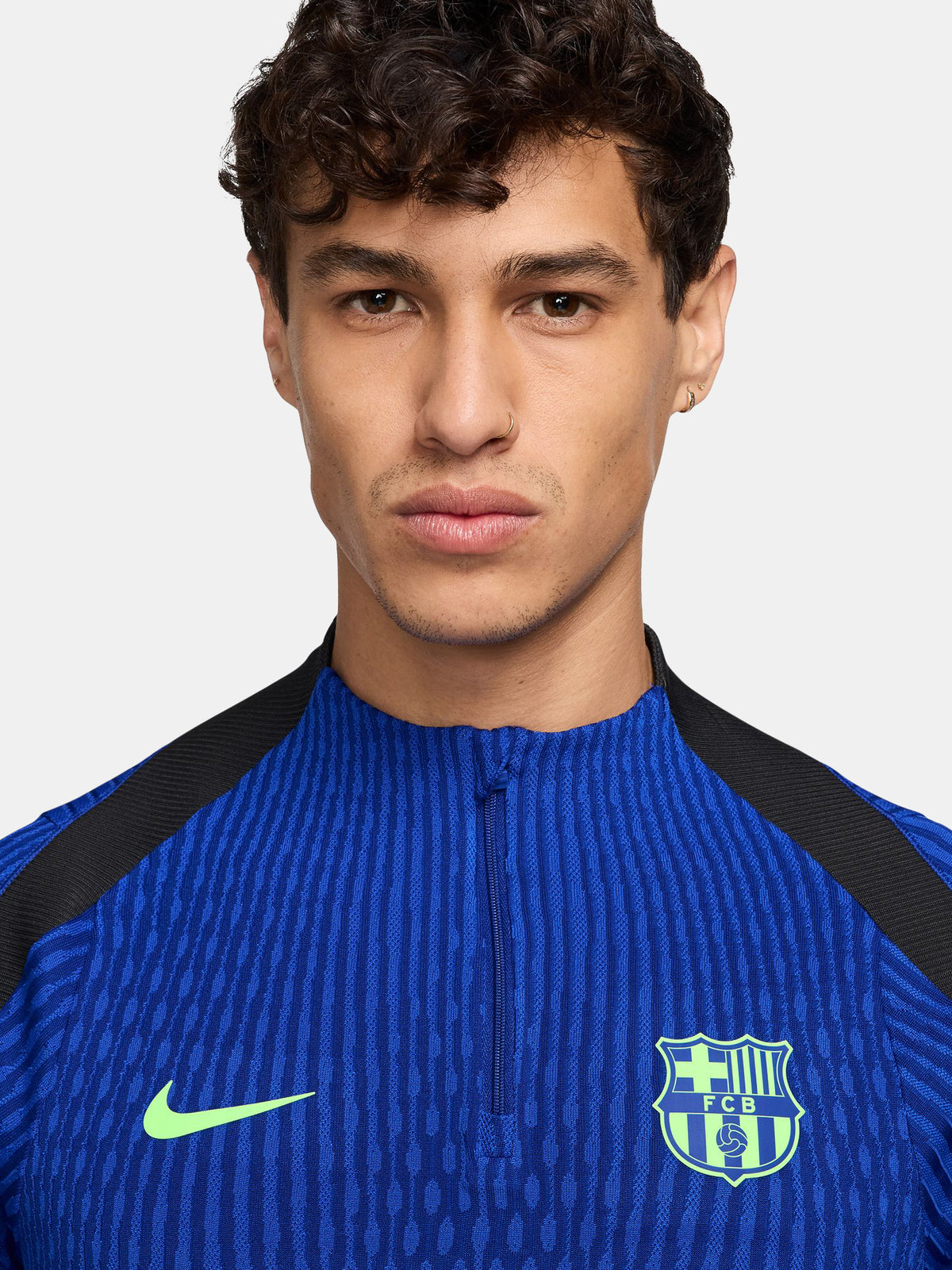 FC Barcelona long-sleeve training top in bright royal blue with vertical textured lines. Features neon green Spotify sponsor logo in the center, Nike logo on the right chest, and FC Barcelona crest on the left chest. Shoulders and upper sleeves have black accents.