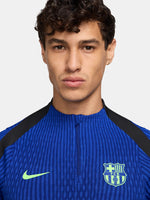 FC Barcelona long-sleeve training top in bright royal blue with vertical textured lines. Features neon green Spotify sponsor logo in the center, Nike logo on the right chest, and FC Barcelona crest on the left chest. Shoulders and upper sleeves have black accents.