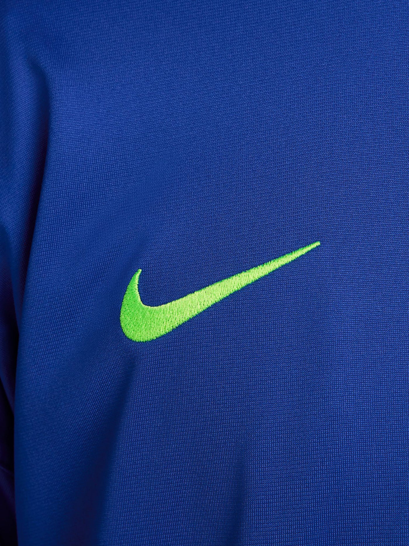 FC Barcelona blue full-zip training jacket featuring neon green Nike logo on the right chest and the FC Barcelona crest with Spotify sponsor on the left chest. Black accents on the lower sleeves. Paired with black training pants.
