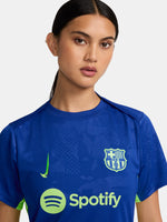 Women's FC Barcelona blue training jersey with neon green logos and side details.