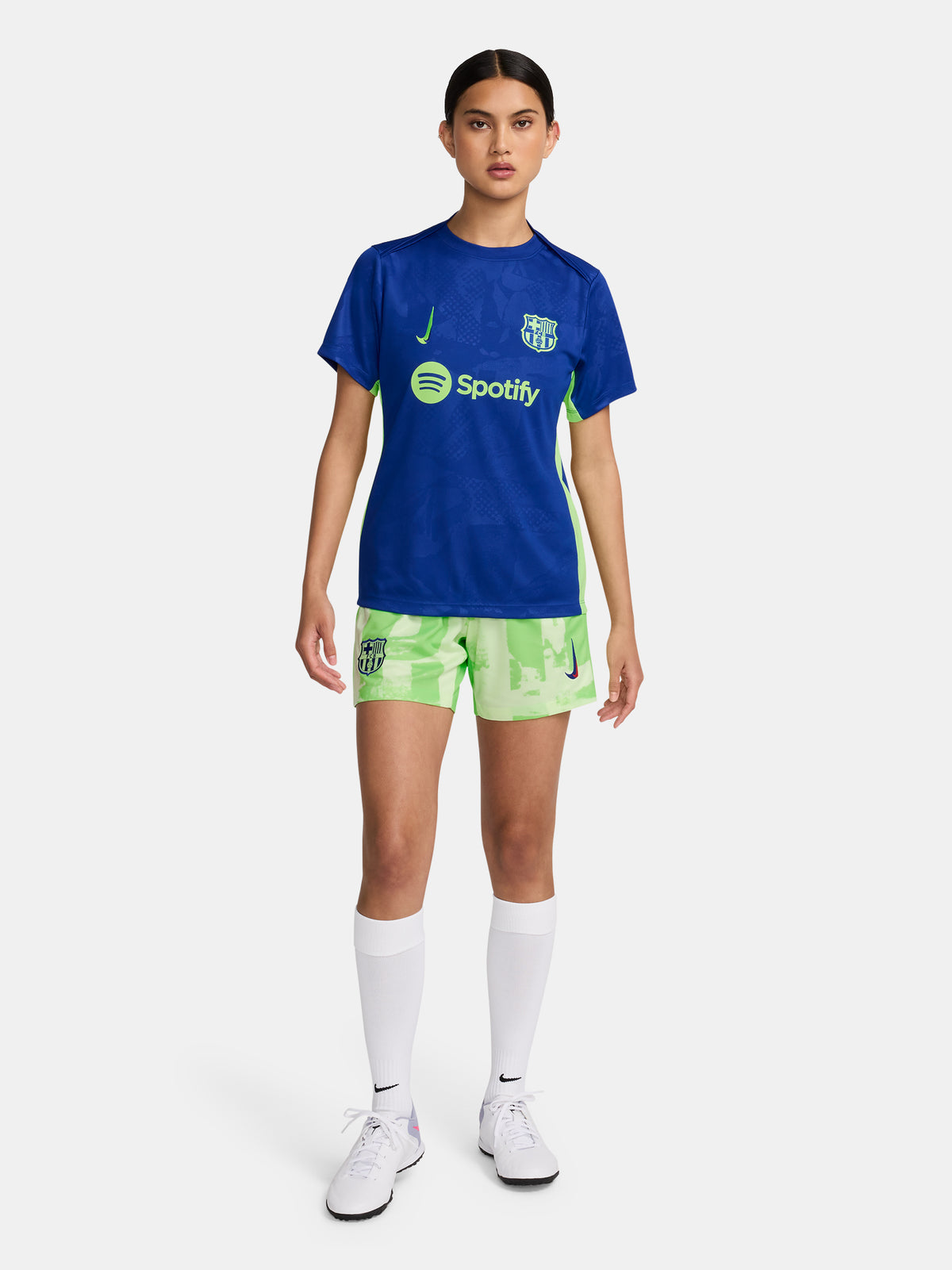 Women's FC Barcelona blue training jersey with neon green logos and side details.