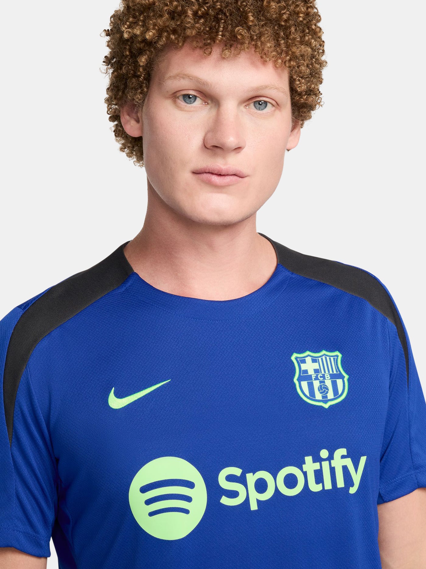 FC Barcelona training shirt in bright royal blue with black shoulder panels. The shirt features neon green logos: a Nike swoosh on the right chest, the FC Barcelona crest on the left chest, and the Spotify sponsor logo prominently across the center.