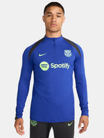 Men's FC Barcelona training kit consisting of a blue long-sleeve top with neon green Nike, Spotify, and club logos, paired with black training pants featuring matching neon green branding.