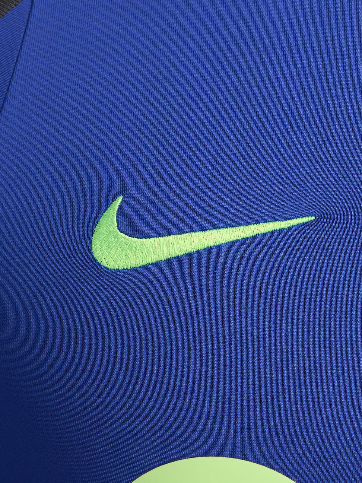 Men's FC Barcelona training kit consisting of a blue long-sleeve top with neon green Nike, Spotify, and club logos, paired with black training pants featuring matching neon green branding.