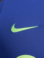Men's FC Barcelona training kit consisting of a blue long-sleeve top with neon green Nike, Spotify, and club logos, paired with black training pants featuring matching neon green branding.