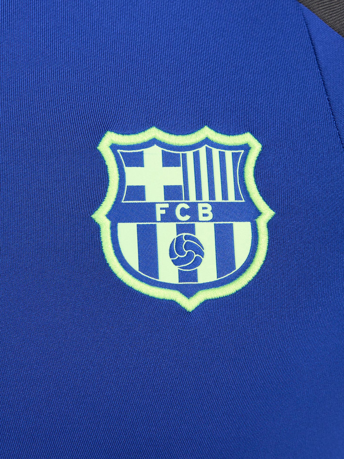Men's FC Barcelona training kit consisting of a blue long-sleeve top with neon green Nike, Spotify, and club logos, paired with black training pants featuring matching neon green branding.