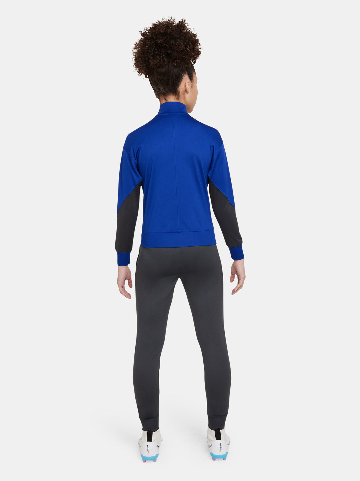 Women's FC Barcelona tracksuit featuring a blue zip-up jacket with neon green Nike and club logos, and dark grey pants with matching neon green details.




