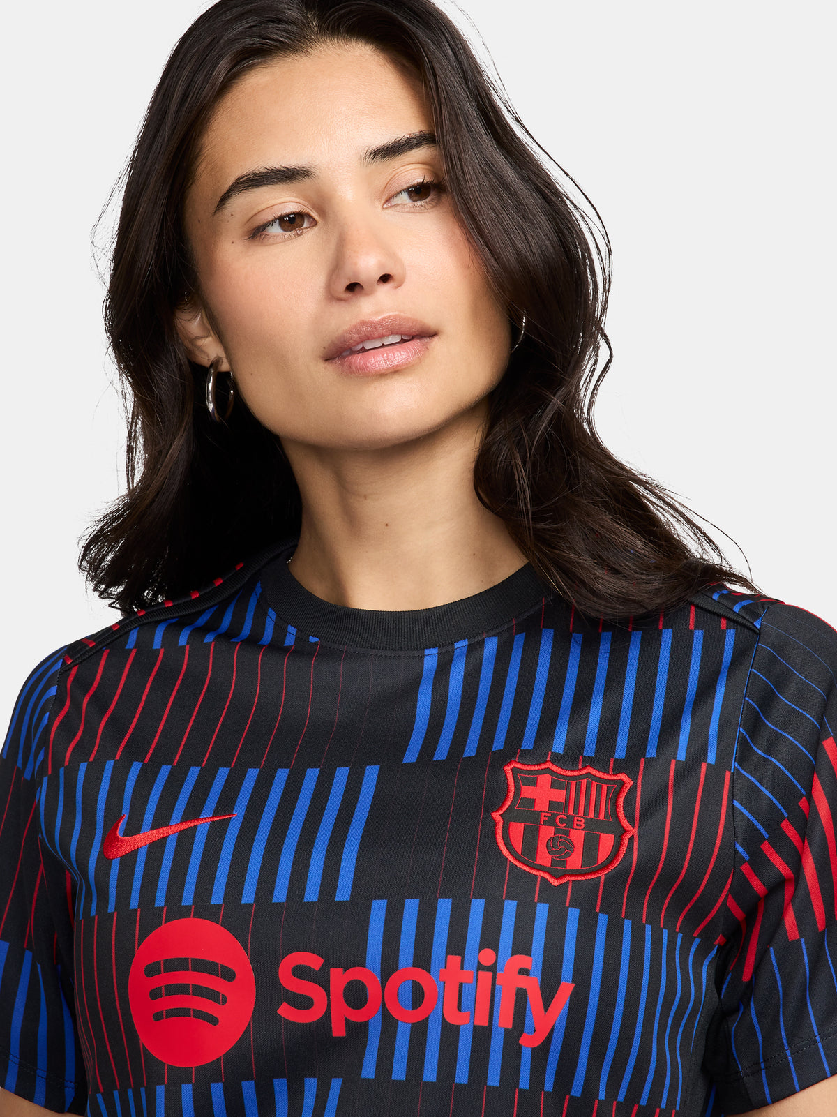 FC Barcelona warm-up shirt featuring a black base with a striking vertical stripe pattern in alternating red and blue. The shirt displays the red Spotify logo in the center, along with the Nike swoosh and FC Barcelona crest, also in red.