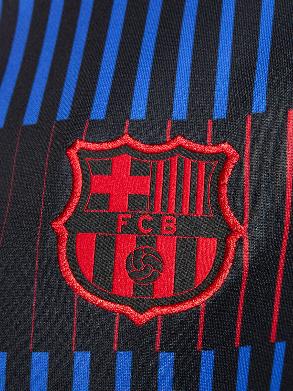 FC Barcelona warm-up shirt featuring a black base with a striking vertical stripe pattern in alternating red and blue. The shirt displays the red Spotify logo in the center, along with the Nike swoosh and FC Barcelona crest, also in red.