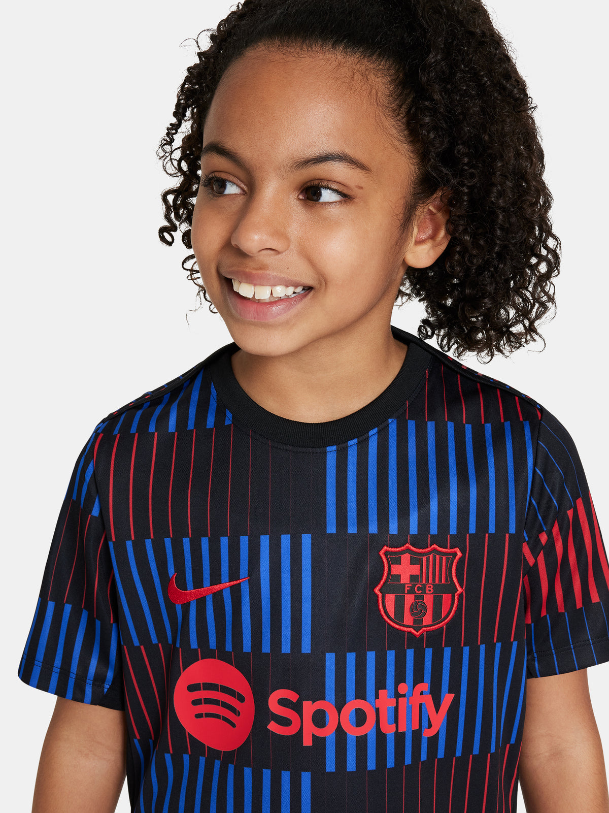 FC Barcelona warm-up shirt featuring a black base with a striking vertical stripe pattern in alternating red and blue. The shirt displays the red Spotify logo in the center, along with the Nike swoosh and FC Barcelona crest, also in red.