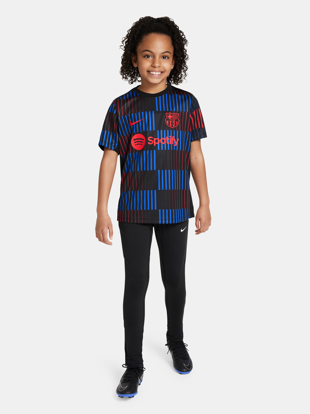 FC Barcelona warm-up shirt featuring a black base with a striking vertical stripe pattern in alternating red and blue. The shirt displays the red Spotify logo in the center, along with the Nike swoosh and FC Barcelona crest, also in red.