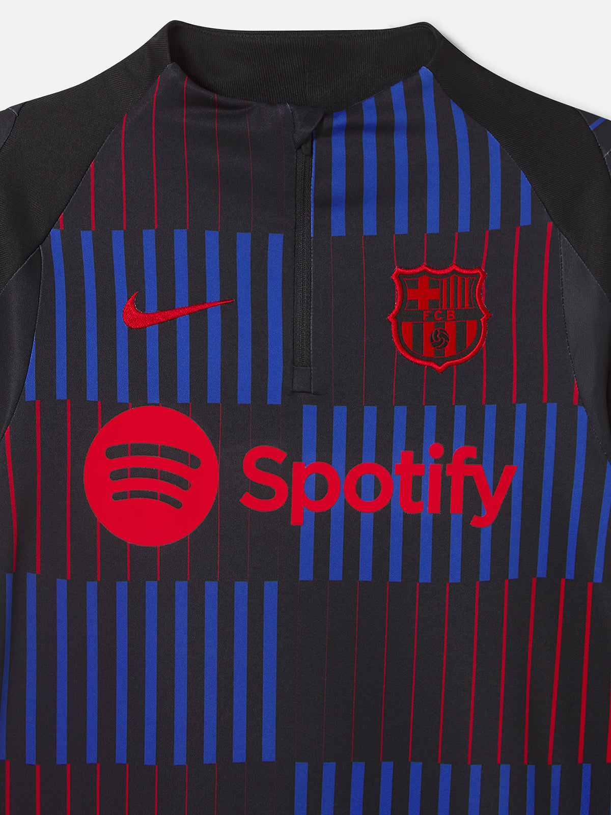 Long-sleeve FC Barcelona training top in black, featuring a dynamic vertical pattern of red and blue stripes on the front. Includes the red Nike logo, red Spotify sponsor logo, and the FC Barcelona crest in red.