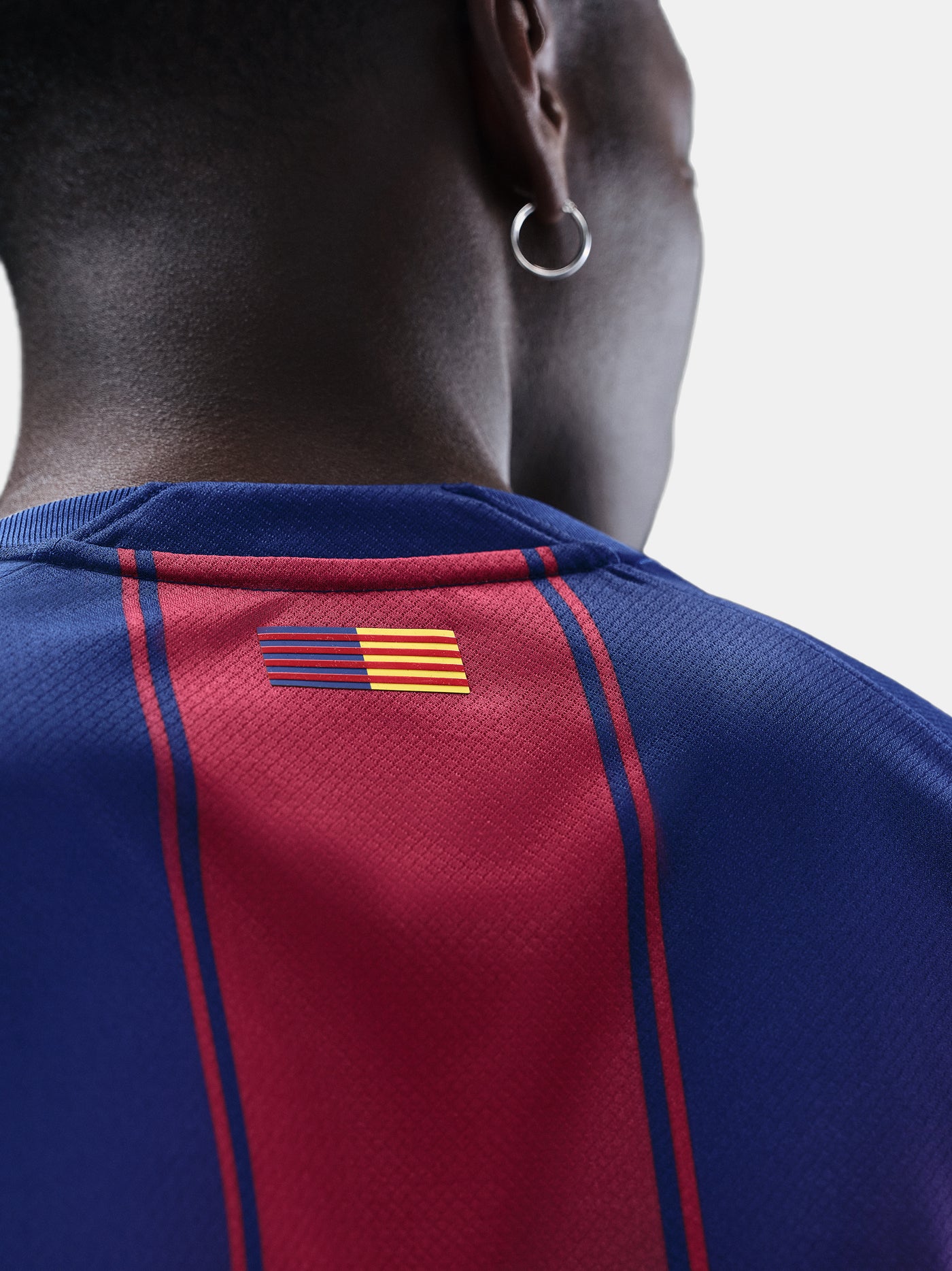 "Detail of the back neck of the FC Barcelona 2025/26 home jersey showing the Catalan flag in blue, red, and yellow stripes."


