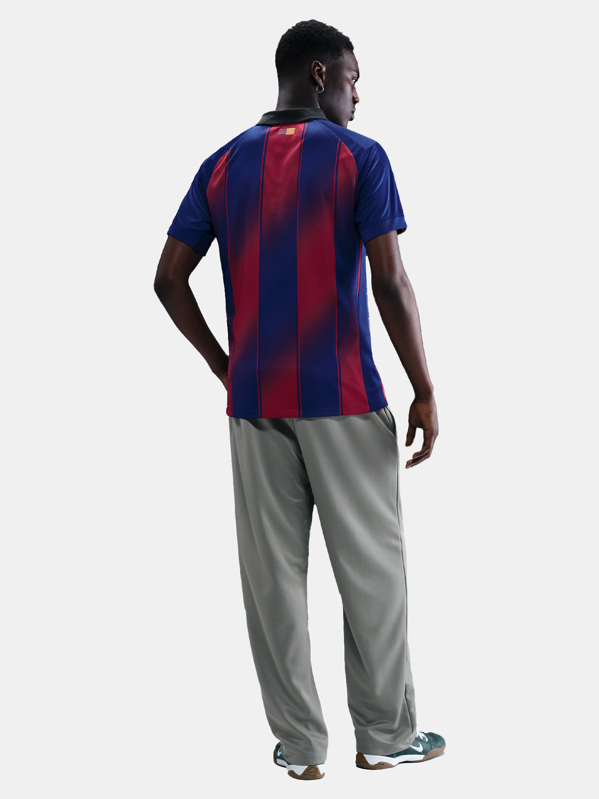 Man wearing the FC Barcelona home jersey in blue and red vertical stripes with black collar, featuring the Nike logo, club crest, and Assistència Sanitària sponsor.