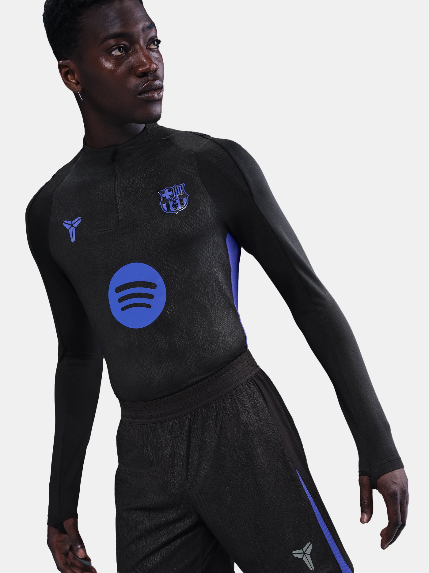 Person wearing a black athletic outfit with logos on a plain background