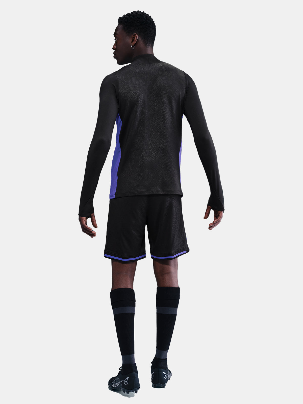 Person wearing a black athletic outfit with purple accents on a white background