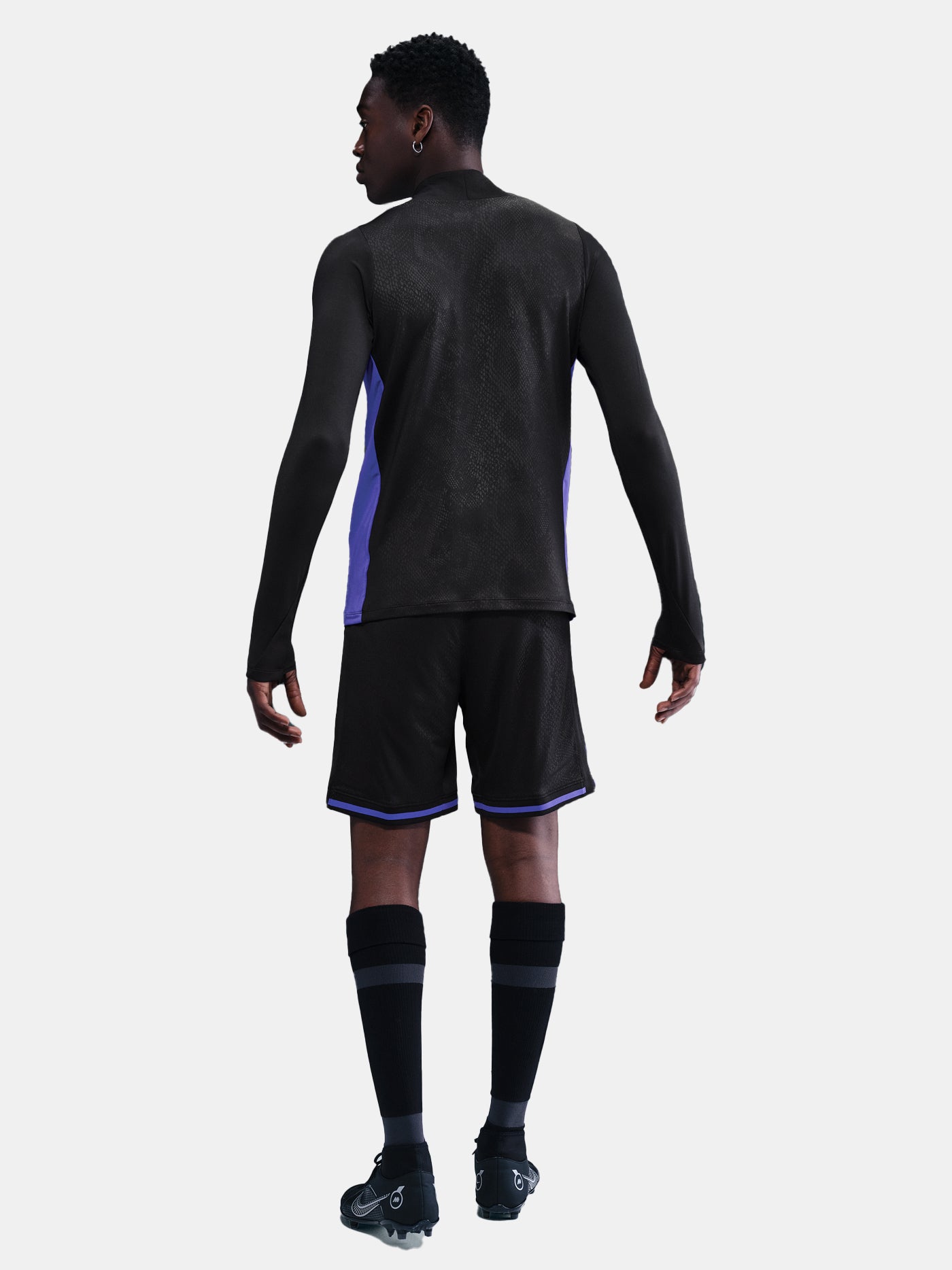 Person wearing a black athletic outfit with purple accents on a white background