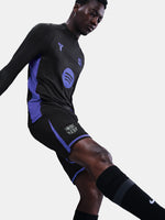 Person wearing a black and blue sports outfit with visible branding on a light gray background