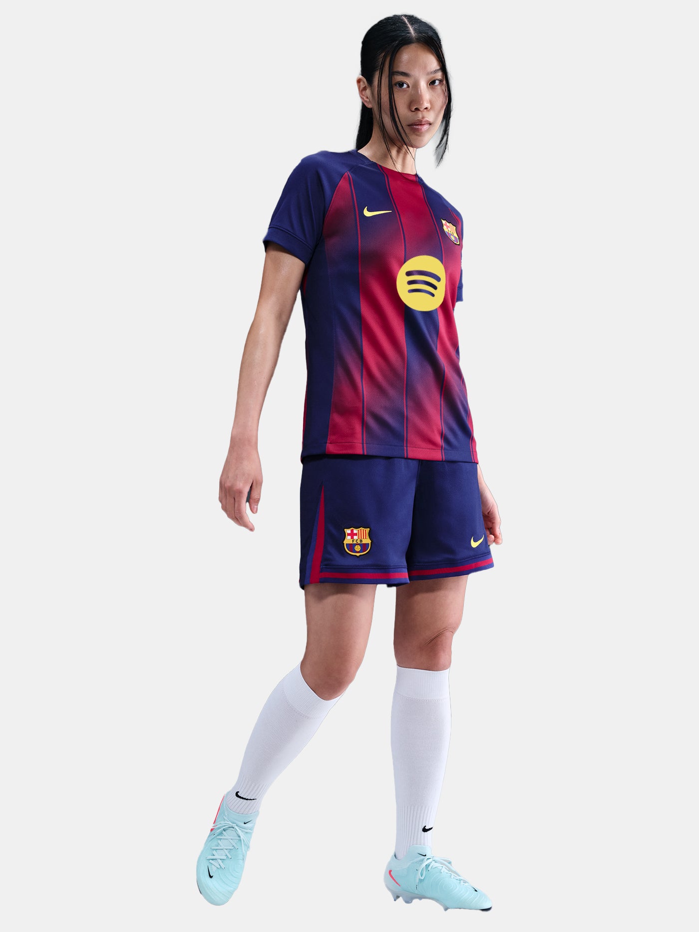 Close-up shot of navy blue shorts with red details and embroidered FC Barcelona and Nike logos, worn by a standing person against a white background.
