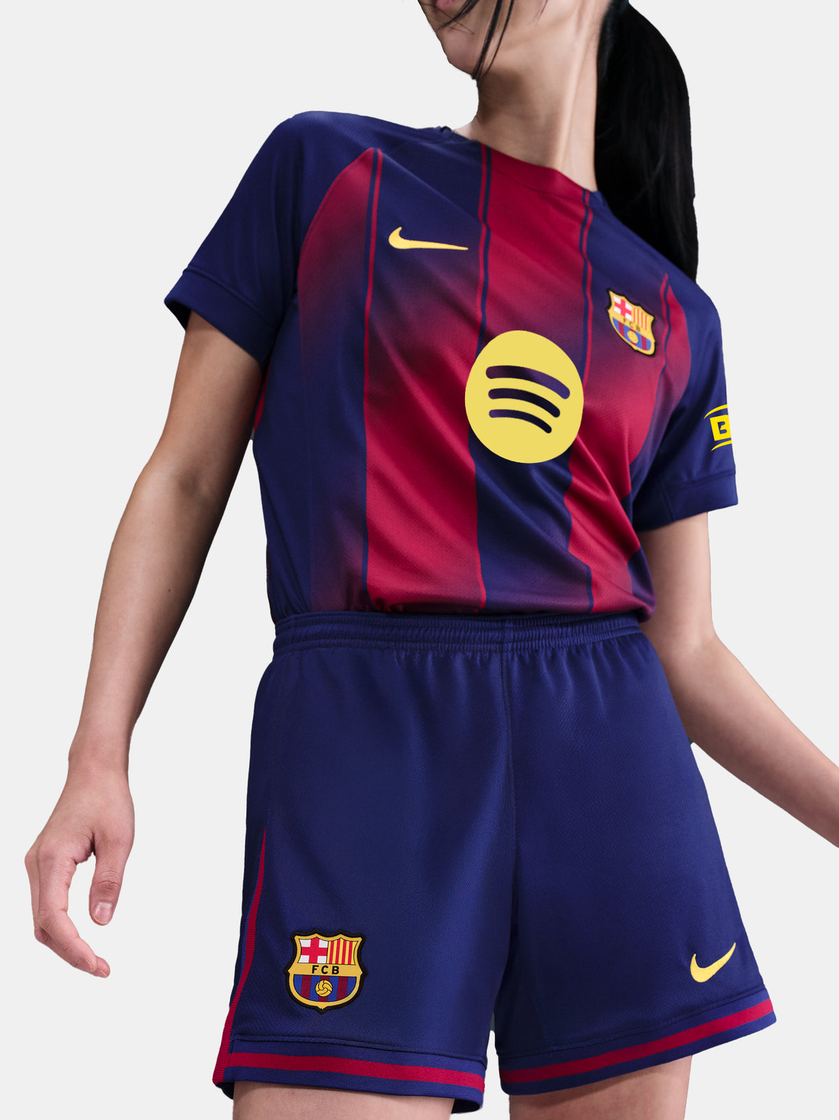 Close-up shot of navy blue shorts with red details and embroidered FC Barcelona and Nike logos, worn by a standing person against a white background.
