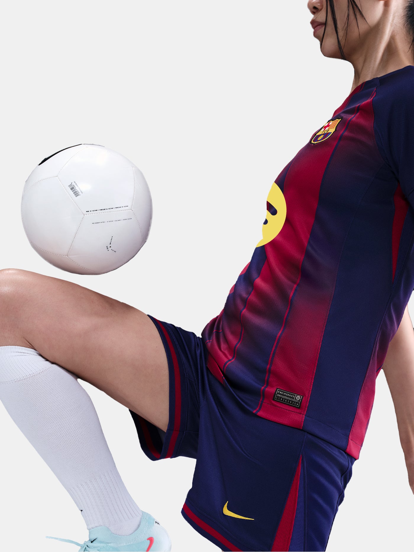 Close-up shot of navy blue shorts with red details and embroidered FC Barcelona and Nike logos, worn by a standing person against a white background.
