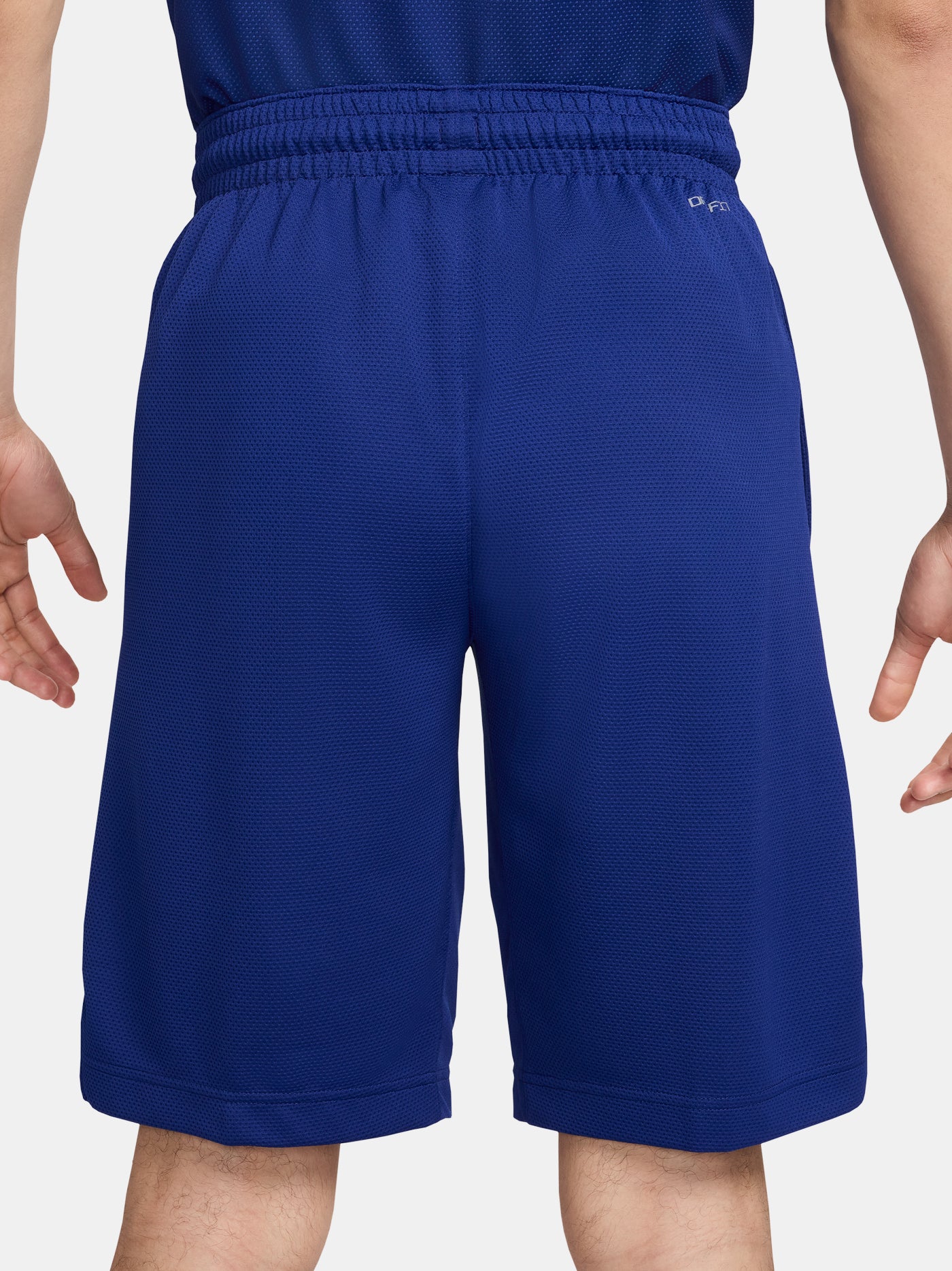Man wearing blue FC Barcelona shorts featuring the club crest and Nike logo.