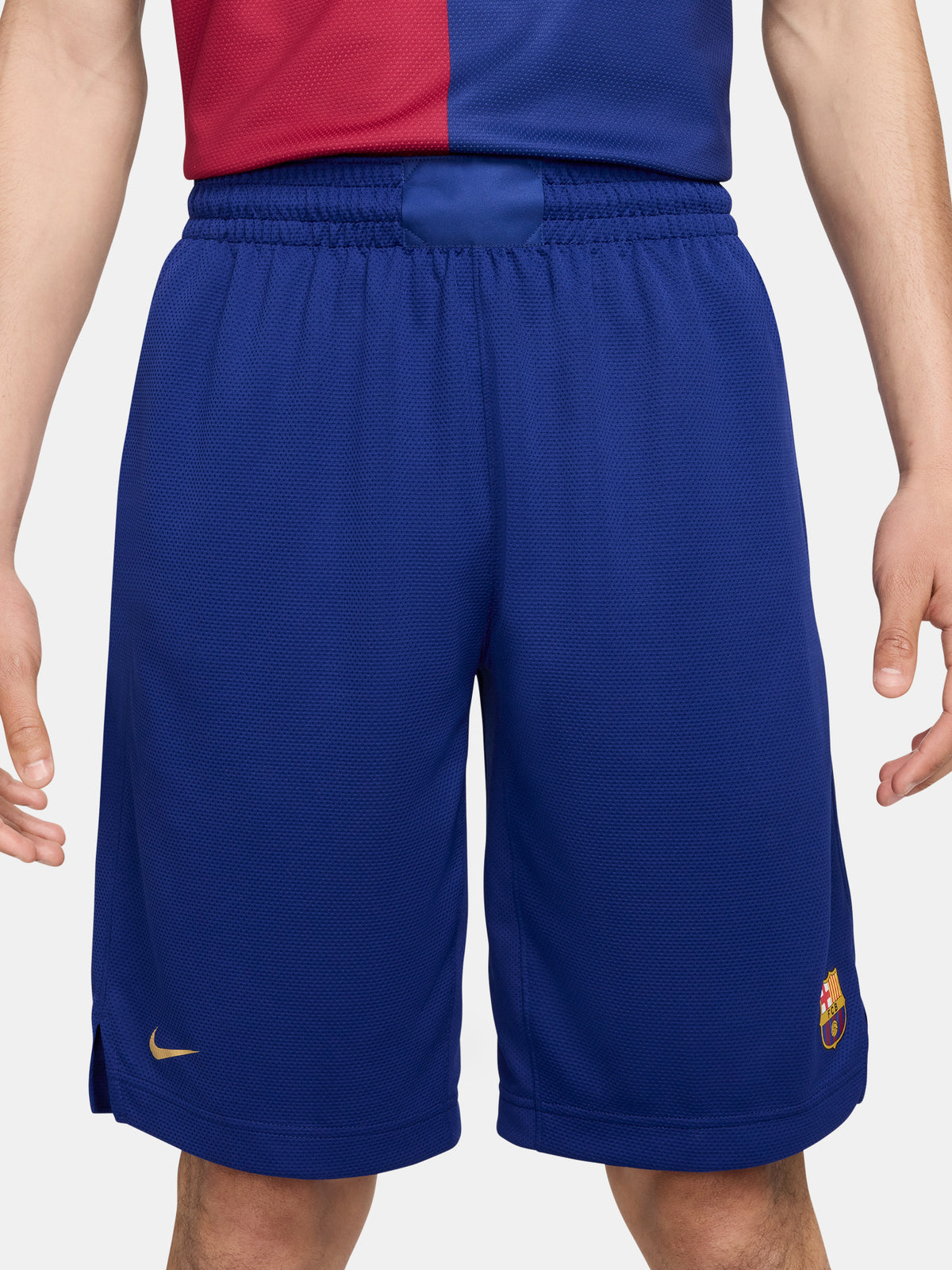Man wearing blue FC Barcelona shorts featuring the club crest and Nike logo.