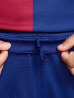 Man wearing blue FC Barcelona shorts featuring the club crest and Nike logo.