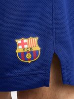 Man wearing blue FC Barcelona shorts featuring the club crest and Nike logo.