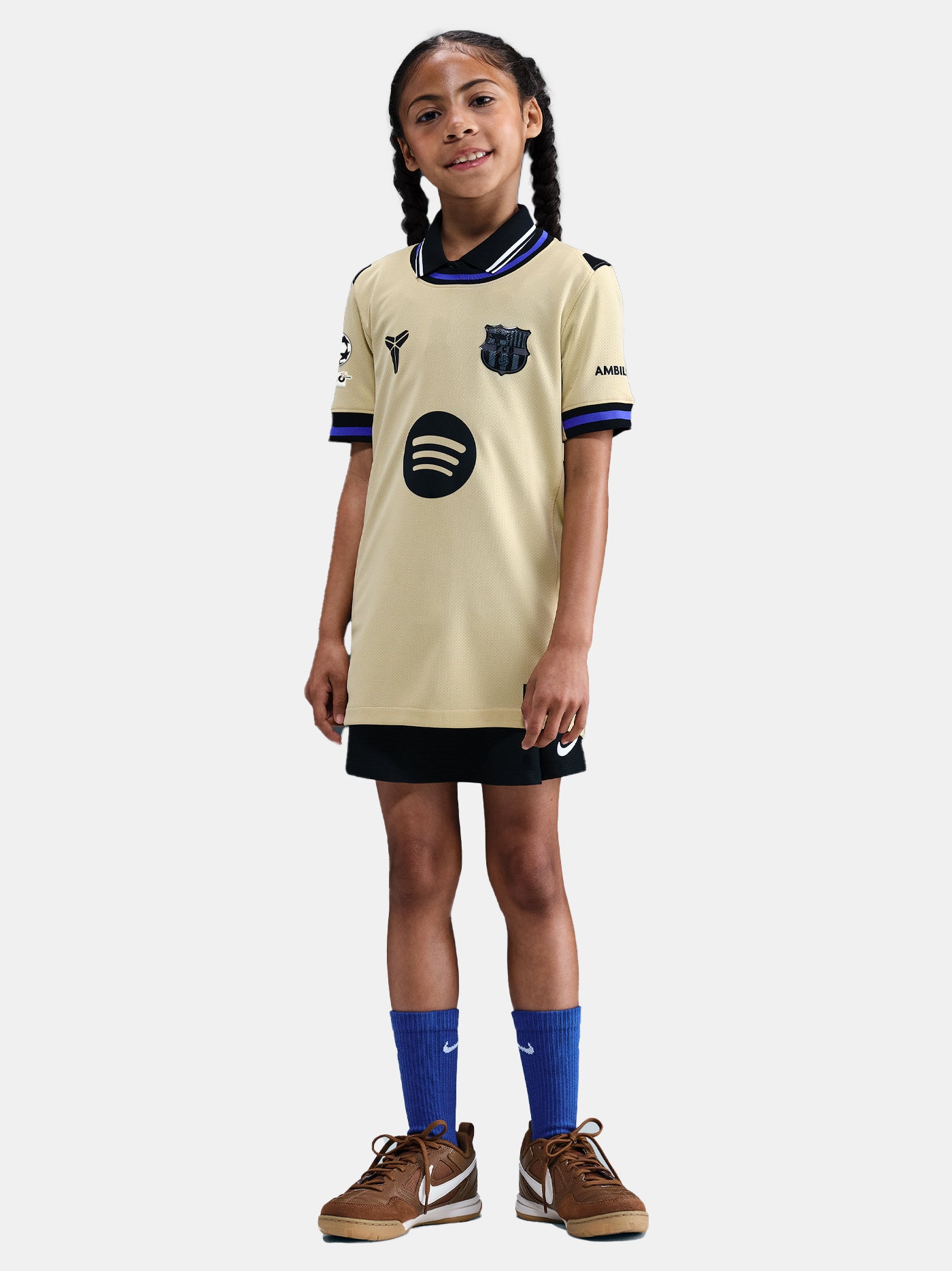 Young girl wearing a beige sports jersey with a logo on a white background